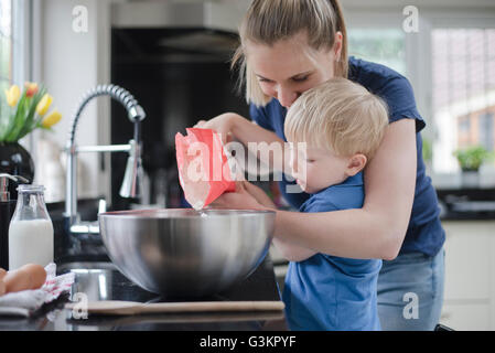 Mother helping son bake cake Stock Photo