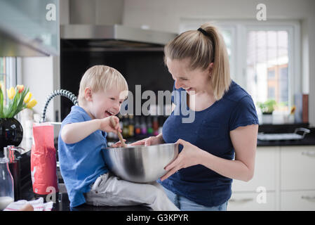 Mother and son fooling around whilst baking, stirring mixture in mixing bowl