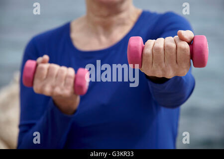 Mature woman outdoors, exercising with hand weights Stock Photo