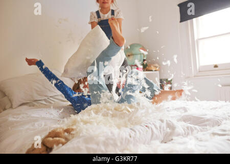 Two sister having feather pillow fight on bed Stock Photo