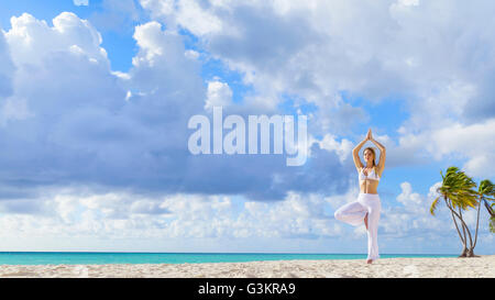 Young woman practising yoga tree pose on beach, Dominican Republic, The Caribbean Stock Photo