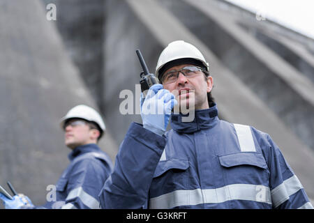 Worker using walkie talkie at foot of dam at hydroelectric power station Stock Photo