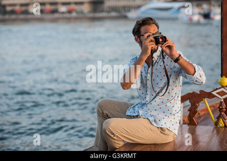 Young man photographing from boat at Dubai marina, United Arab Emirates Stock Photo