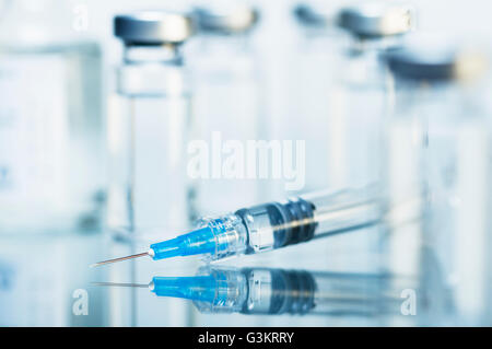Syringe. Disposable plastic medical syringe surrounded by sealed medication vials Stock Photo
