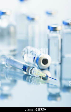 Syringe. Disposable plastic medical syringe surrounded by sealed medication vials Stock Photo