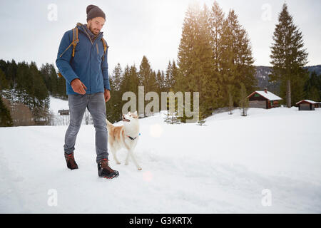 Young man walking husky in snow covered landscape, Elmau, Bavaria, Germany Stock Photo