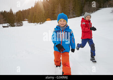 Boy and brother running in snow covered landscape, Elmau, Bavaria, Germany Stock Photo
