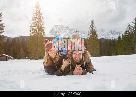Portrait of parents and sons lying in snow covered landscape, Elmau, Bavaria, Germany Stock Photo