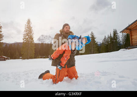 Father lifting up son in snow, Elmau, Bavaria, Germany Stock Photo