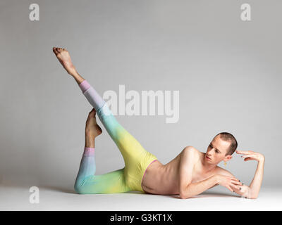 Young male dancer wearing multi- coloured leggings poised on studio floor Stock Photo