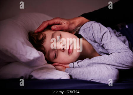 Mothers hand stroking sleeping boy Stock Photo