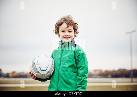 Boy holding football looking at camera smiling Stock Photo