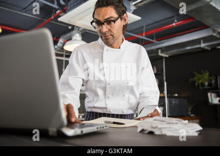 Chef in restaurant using laptop Stock Photo