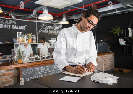 Chef in restaurant writing in notepad Stock Photo