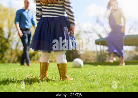 Low section of girl in garden with family playing with football Stock Photo