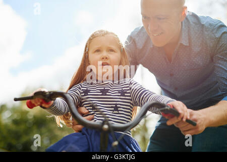 Father teaching daughter to ride bicycle Stock Photo