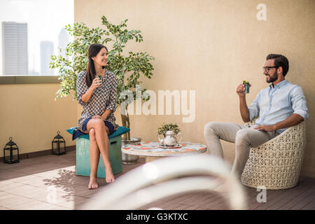 Couple drinking mint tea on hotel room  balcony, Dubai, United Arab Emirates Stock Photo