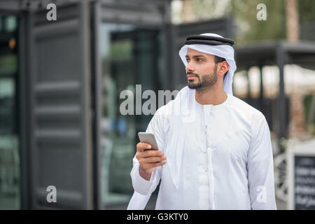 Man wearing traditional middle eastern clothing using smartphone, Dubai, United Arab Emirates Stock Photo