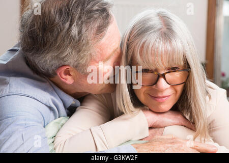 Man whispering into wife's ear Stock Photo