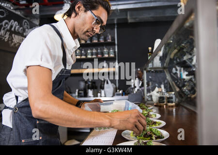 Restaurateur preparing salad behind service counter Stock Photo