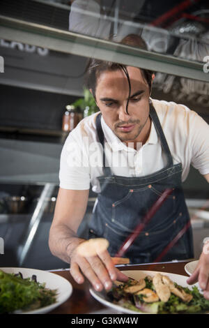 Restaurateur preparing salad behind service counter Stock Photo