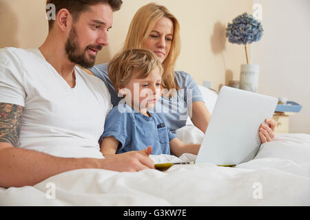 Mother and father in bed with son using digital tablet Stock Photo