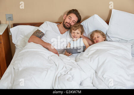 Father and sons in bed using digital tablet Stock Photo
