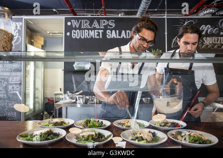 Restaurateurs preparing salad behind service counter Stock Photo