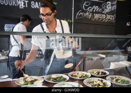 Restaurateurs preparing salad behind service counter Stock Photo