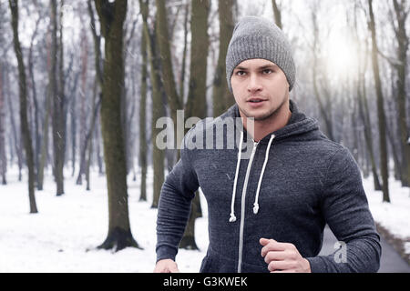 Young man jogging through snowy forest Stock Photo