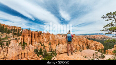 Hiker with backpack in bizarre landscape, reddish rocky landscape with fairy chimneys, sandstone formations Stock Photo