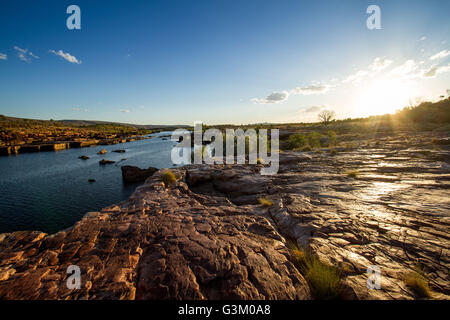 Sunset over a rocky river landscape in Mornington Nature Reserve, Western Australia, with flowing water, rugged terrain, and open savanna Stock Photo