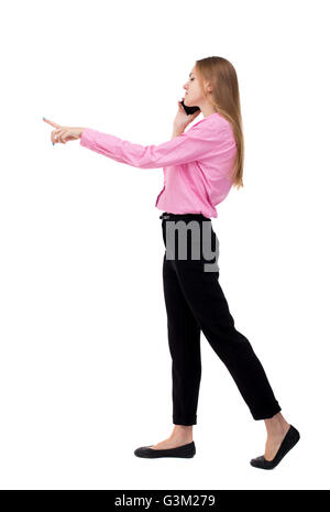 back view of walking business woman . beautiful girl going, pointing and talking on smartphone. backside view of person. Rear view people collection. Isolated over white background. Girl businessman checks the information on the tablet. Stock Photo