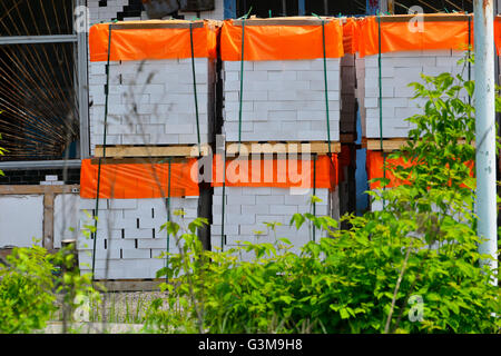 White clay bricks, stacked on pallets in an open warehouse Stock Photo
