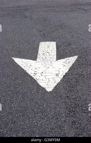 White arrow painted on dark pavement Stock Photo