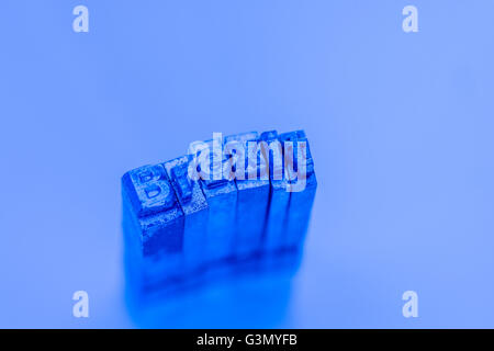 Brexit concept / visual metaphor represented by macro-photo of lead typeface lit by blue light on neutral intensity background. No-Deal Brexit. Stock Photo