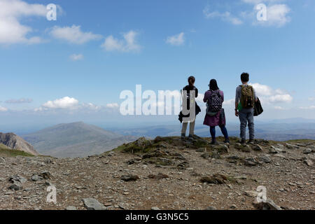 Landscape image of three walkers taking in the view on the summit of Mount Snowdon Stock Photo