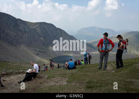Landscape image of couple admiring the daytime view of surrounding mountains and lakes from Mount Snowdon Stock Photo