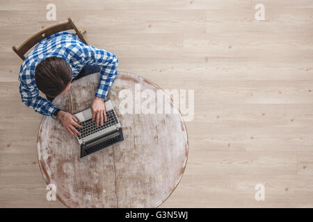 Man working on a wooden table with laptop, top view Stock Photo