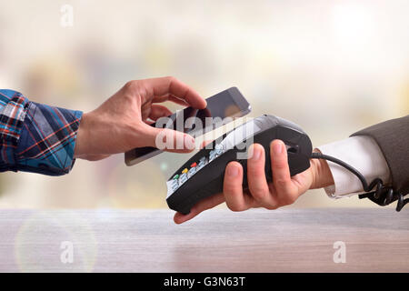 Customer paying a merchant with mobile phone with NFC technology. Top view. Horizontal composition. Stock Photo