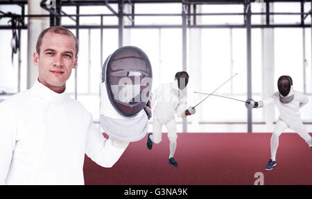 Composite image of swordsman holding fencing mask Stock Photo