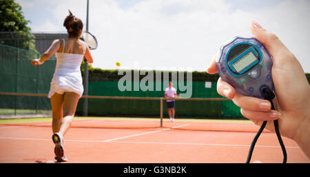 Close up of woman is holding a stopwatch against tennis match in progress Stock Photo