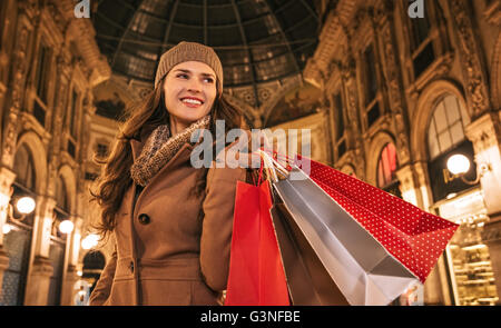 Get ready to making your way through shopping addicted crowd. Huge winter sales in Milan just started. Happy young woman with shopping bags standing in Galleria Vittorio Emanuele II and looking aside Stock Photo