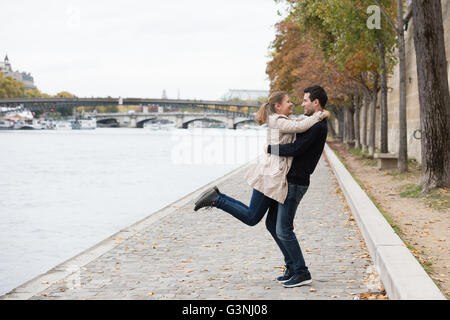 young happy couple man and woman on the riverside of Seine, Paris, France Stock Photo