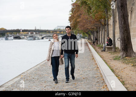 young happy couple man and woman on the riverside of Seine, Paris, France Stock Photo