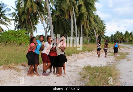 Local girls walking along the road in the evening, Christmas Island, Kiribati Stock Photo