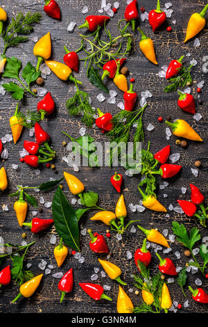 flat lay of decorative spices, dry peppers, sea salt, different greenery on cracks black background, close up Stock Photo
