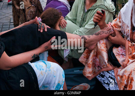 Girl getting a henna tattoo on her foot and ankle by a local woman in the Djemaa El Fna courtyard, Marrakech, Morocco, Africa Stock Photo