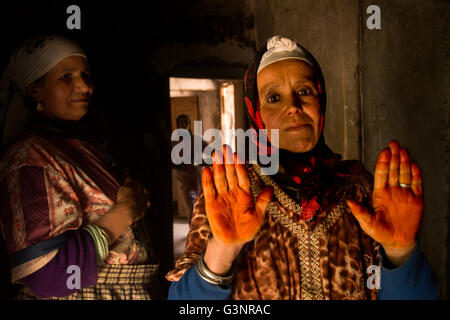 A Berber woman shows her henna stained hands which signifies beauty, while her mother looks on from the sidelines Stock Photo