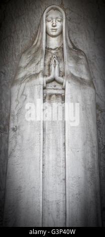 Old statue of Virgin Mary with clasped hands Stock Photo